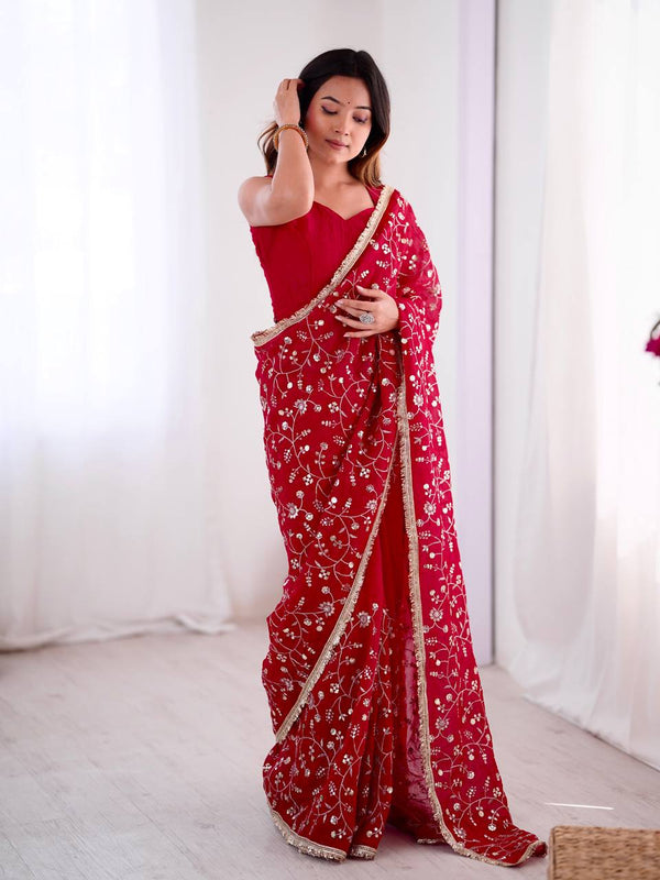 Red embroidered saree with intricate golden floral design and matching blouse, perfect for weddings and festive occasions – model showcasing full look indoors.

Woman wearing an elegant red embroidered saree with golden border, posing indoors with soft white curtains in the background.

