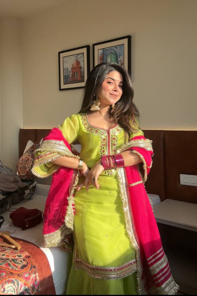 "Smiling woman wearing a vibrant green sharara suit with silver gota work and bold red dupatta – festive traditional Indian outfit for weddings and cultural celebrations."

"Green sharara set with gota patti embroidery and contrasting red dupatta – designer Indian festive wear for women"

"Green sharara suit with red dupatta – festive ethnic outfit for women"

"Traditional green sharara suit with mirror and gota patti work, styled with red dupatta – perfect for haldi, mehendi, or sangeet functions"




