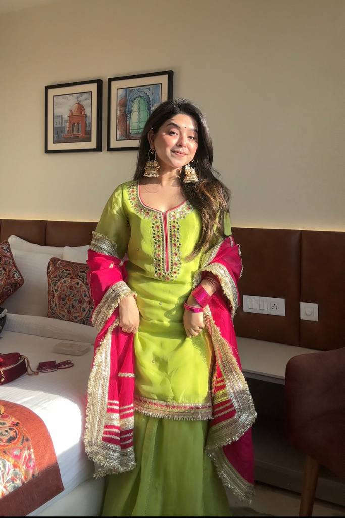 "Young woman wearing lime green sharara suit with mirror work and contrasting red dupatta – perfect traditional outfit for weddings, haldi, and festive occasions."

"Lime green embroidered sharara suit with red dupatta – festive Indian ethnic wear for women"

"Bright green sharara dress with mirror work and red dupatta – ideal for haldi ceremony, sangeet, and traditional parties"

"Green sharara suit with red dupatta – festive ethnic wear for women"


