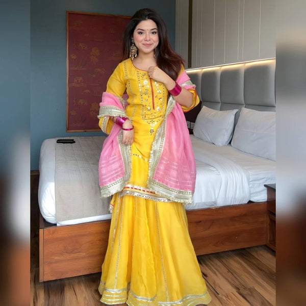 "Stylish woman wearing a vibrant yellow sharara suit with mirror work and pink dupatta – festive traditional Indian outfit for Haldi, Mehndi, or wedding functions."

"Yellow sharara suit with mirror and gota work, styled with pink dupatta – women's festive ethnic wear set"

"Vibrant yellow sharara suit with designer detailing and contrasting pink dupatta – perfect for Haldi ceremony or festive occasions"

"Yellow mirror work sharara suit with pink dupatta for women"

"Shop this stunning yellow sharara suit 