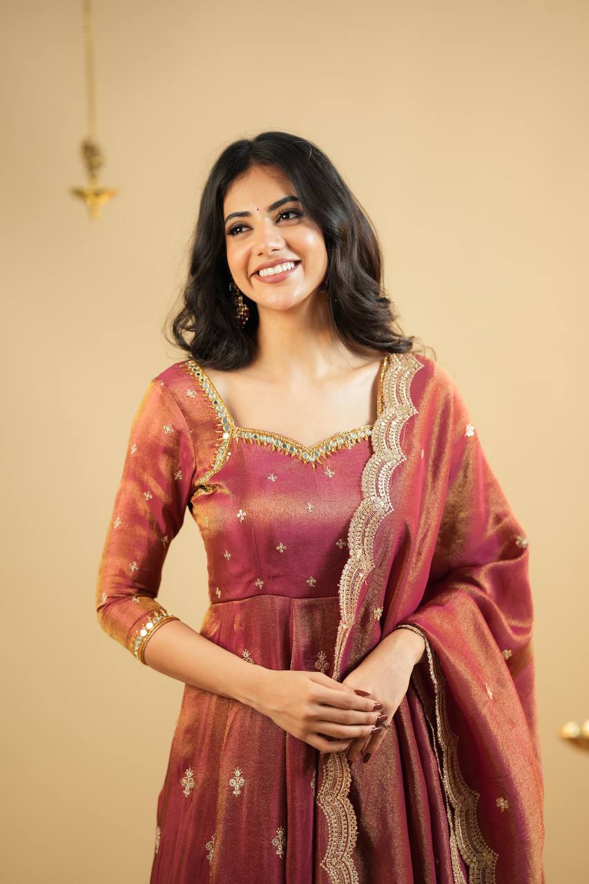 "Smiling woman in rust orange Anarkali dress with traditional golden embroidery and flared hem – perfect festive and ethnic wear for weddings or parties."

"Rust orange embroidered Anarkali gown for women with golden motifs and traditional festive design"

"Elegant ethnic Anarkali suit in rust orange with intricate zari embroidery – festive Indian wear for women"

"Rust orange Anarkali gown with gold embroidery for festive occasions"
